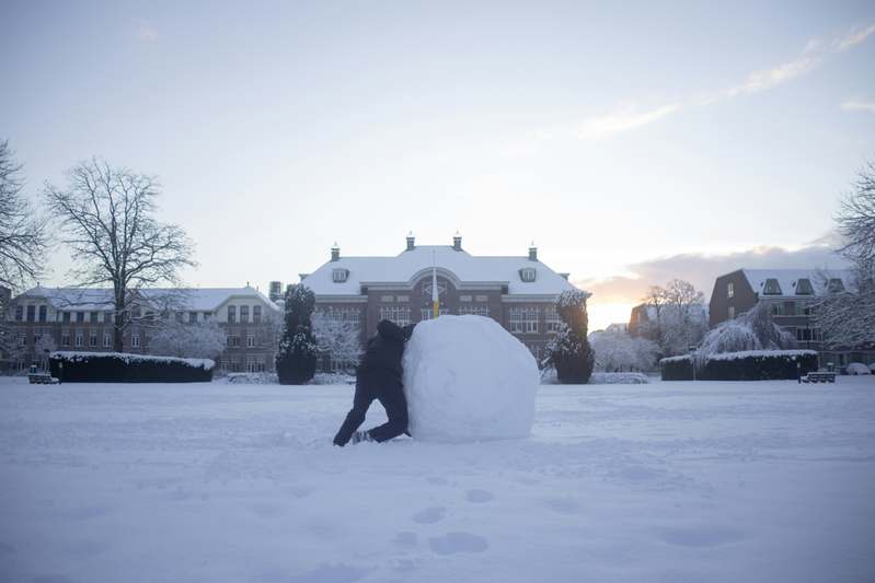 Illustration of a person rolling a growing snowball labeled with debt amounts decreasing over time